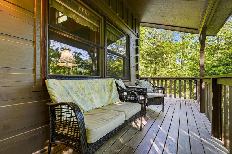 Unwind on your private covered porch with comfortable wicker seating surrounded by lush greenery and dappled sunlight.