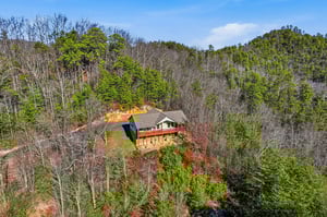 A secluded mountain retreat nestled among rolling hills and vibrant autumn foliage, offering peaceful seclusion in natures embrace.