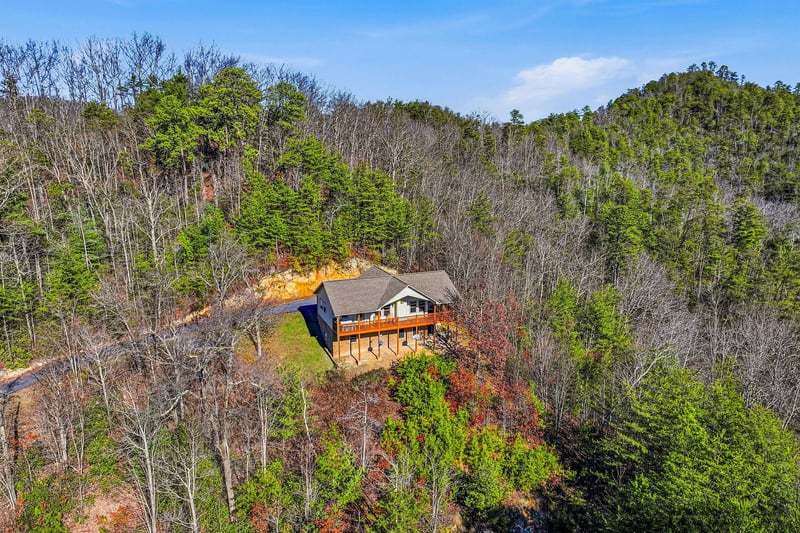 A secluded mountain retreat nestled among rolling hills and vibrant autumn foliage, offering peaceful seclusion in natures embrace.