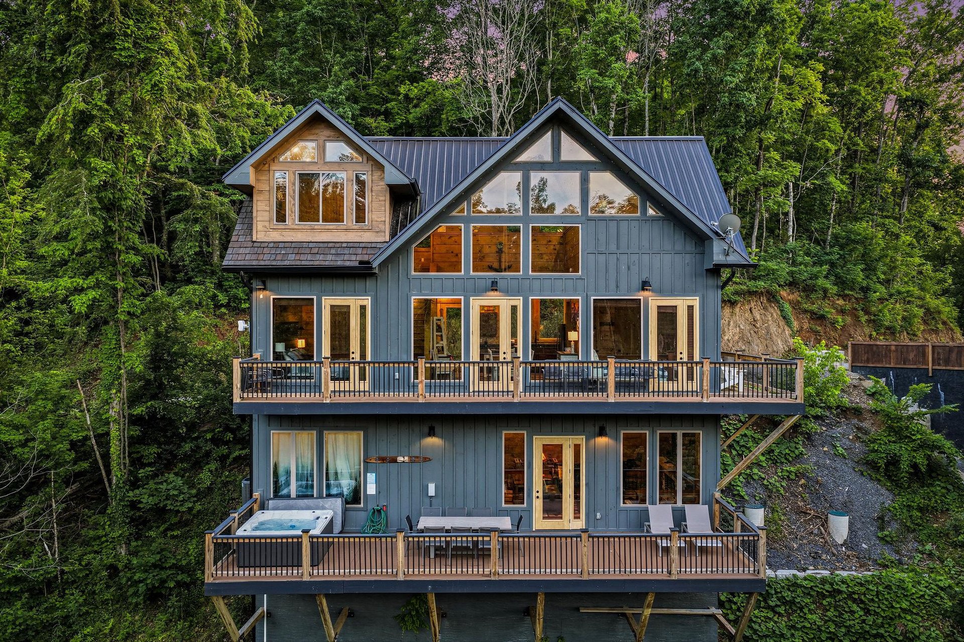This striking architectural retreat is nestled privately in lush forest surroundings, featuring expansive windows, multilevel decks, and a soothing hot tub for ultimate relaxation.