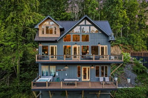 This striking architectural retreat is nestled privately in lush forest surroundings, featuring expansive windows, multilevel decks, and a soothing hot tub for ultimate relaxation.