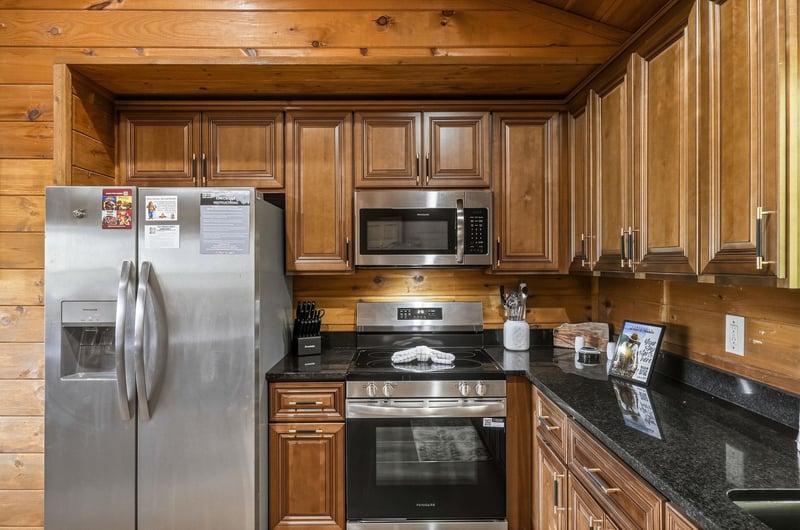 Full kitchen with rich wood cabinets, modern appliances, and sleek granite counters, ready for cooking memorable meals during your stay.