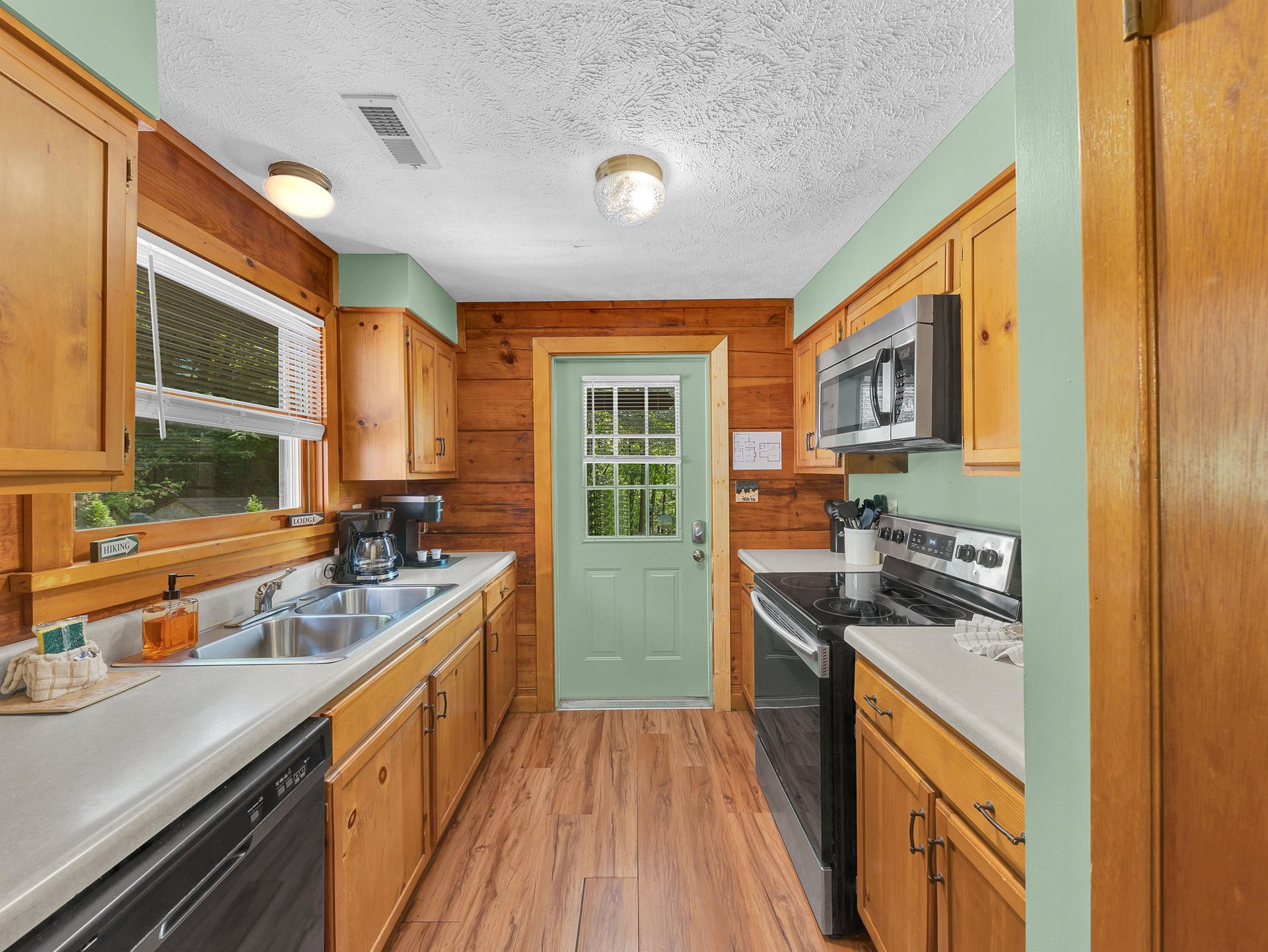 Your fully equipped kitchen features warm wood cabinets, modern appliances, and charming mint green walls that create a cozy cooking space.