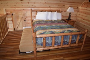 Cozy log cabin bedroom with handcrafted wooden bed and colorful quilt awaits your peaceful mountain retreat.