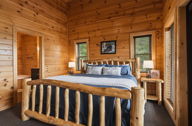 Wrap yourself in the warmth of natural wood as you sink into this handcrafted log bed. Soft blue linens and rustic bear artwork create a cozy mountain retreat where restful sleep comes naturally.