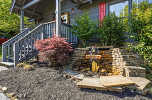 Charming property entrance with stone landscaping and red maple showcases mountain cabin character.