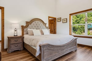 Wake up to natural light streaming through your bedroom window. The plush bed invites restful sleep, while a cozy reading lamp and warm wood accents create a peaceful retreat.