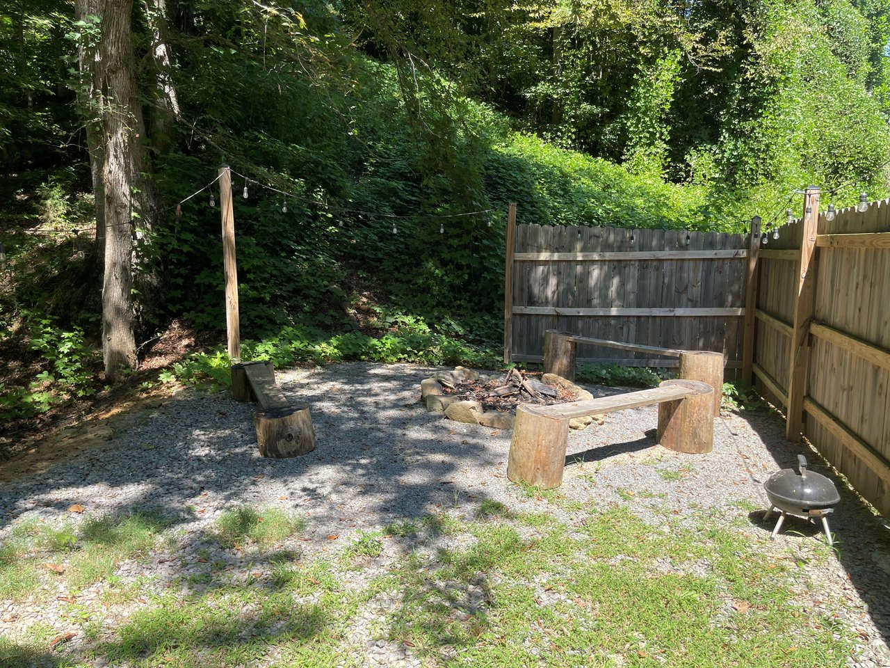 A rustic fire pit nestled in a private, fenced backyard invites you to unwind under the trees. Enjoy evening gatherings around the flames, with a BBQ grill ready for your outdoor feasts.