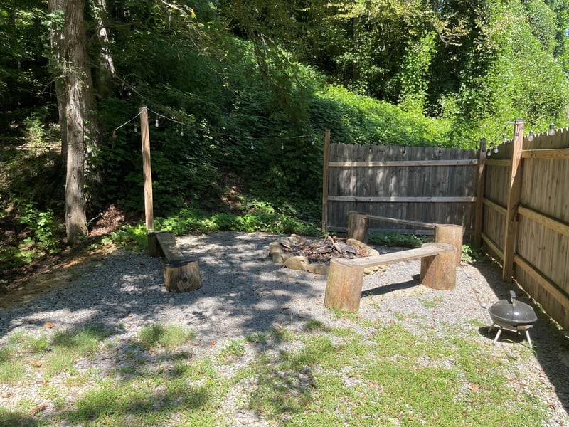 A rustic fire pit nestled in a private, fenced backyard invites you to unwind under the trees. Enjoy evening gatherings around the flames, with a BBQ grill ready for your outdoor feasts.
