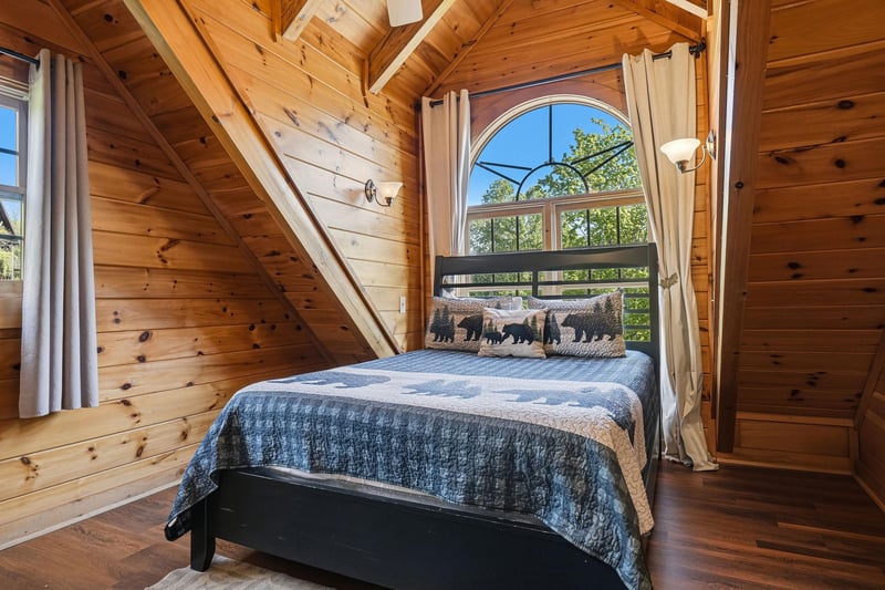 Sleep peacefully in your cozy loft bedroom, where warm knotty pine surrounds you and arched windows frame beautiful treetop views.