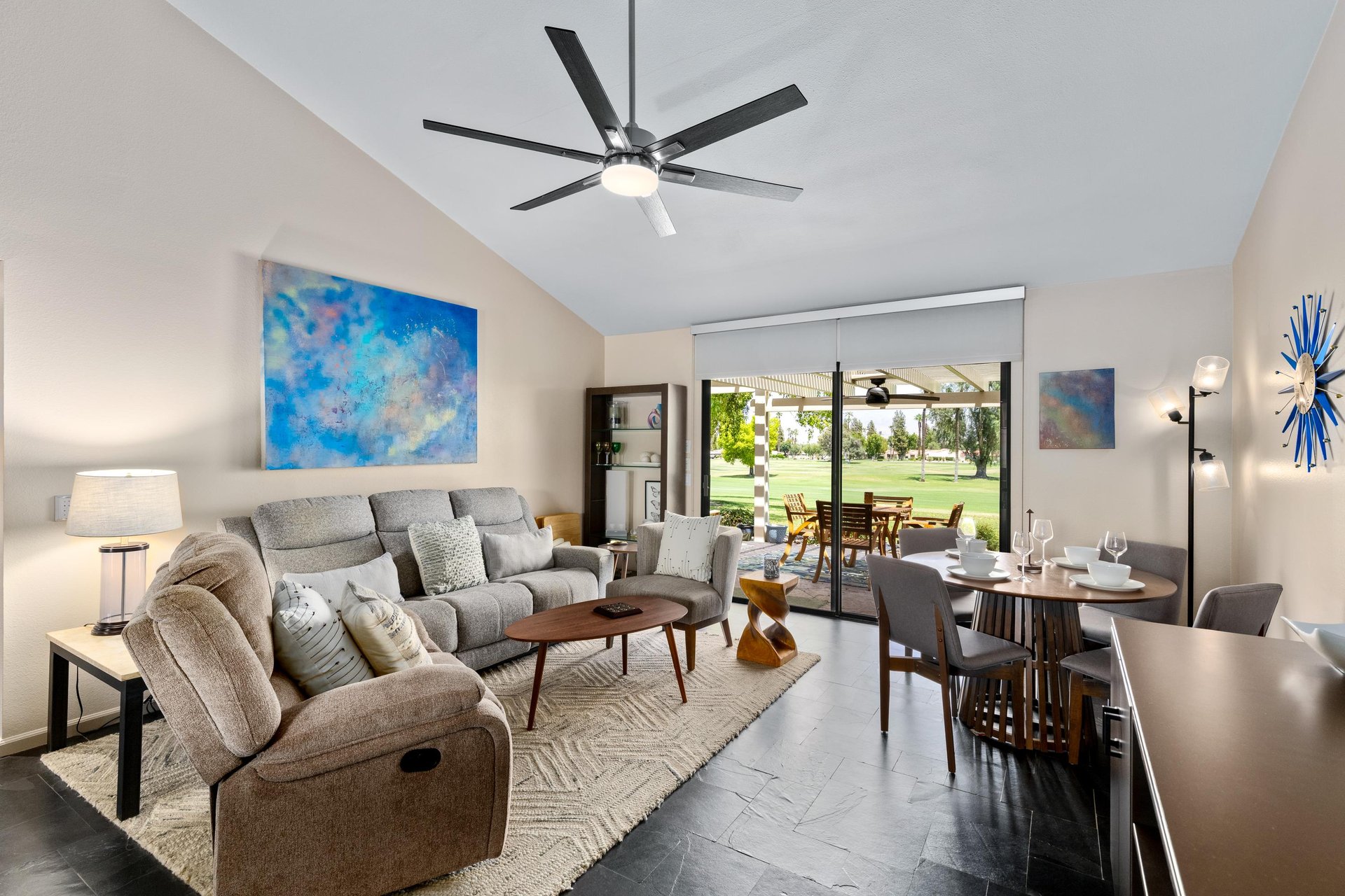 Cozy living room with ample seating, flatscreen TV, dining area, sliding door to patio area, and golf course views.