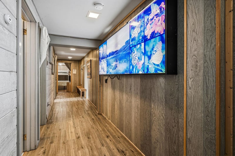 Enjoy entertainment in your spacious hallway featuring a large wallmounted TV and warm wood accents throughout.