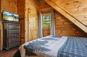 Rest peacefully in your rustic wooden bedroom with vaulted ceilings and forest views through your private window.