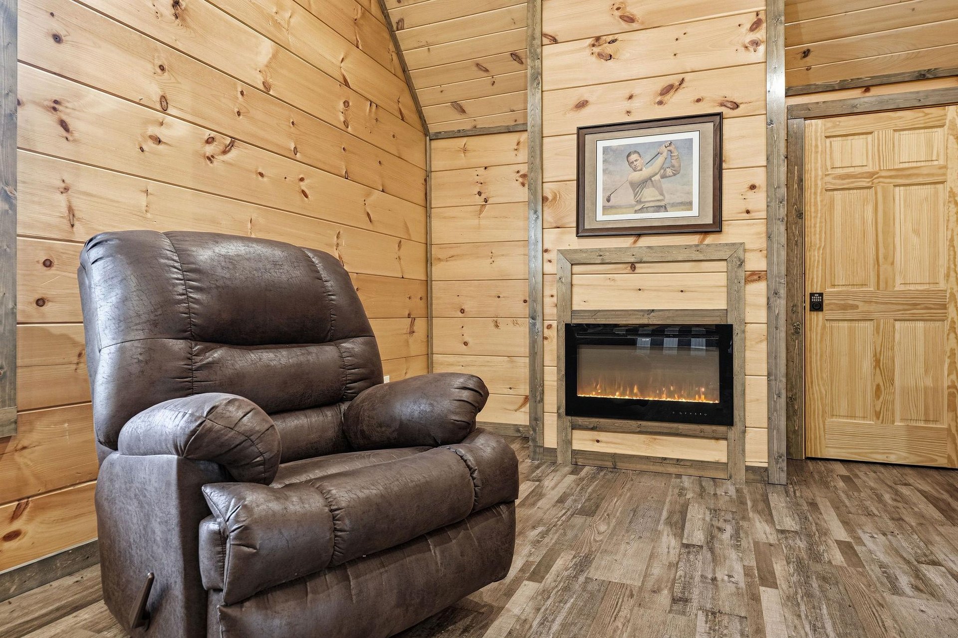 Sink into your plush leather recliner beside the electric fireplace, where rustic wood walls create your perfect retreat for relaxation.