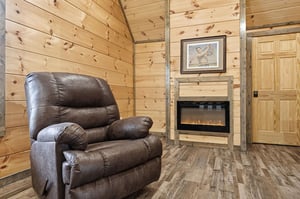 Sink into your plush leather recliner beside the electric fireplace, where rustic wood walls create your perfect retreat for relaxation.
