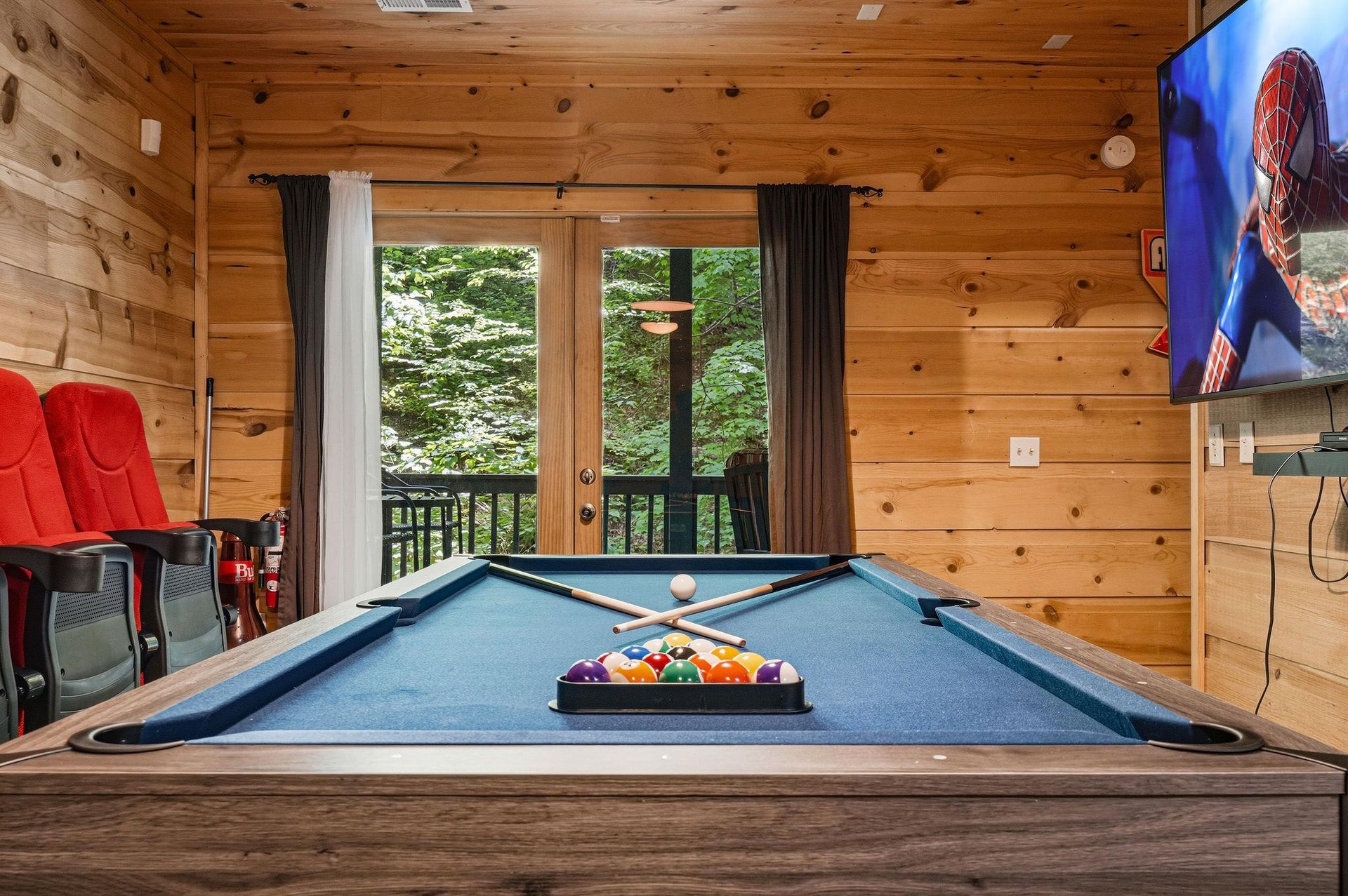 Challenge your friends to a billiards match in this cozy game room, where rustic wood walls and forest views create the perfect retreat for friendly competition.