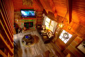 Cozy up in this stunning rustic cabin with soaring vaulted ceilings, stone fireplace, and comfortable seating perfect for movie nights.