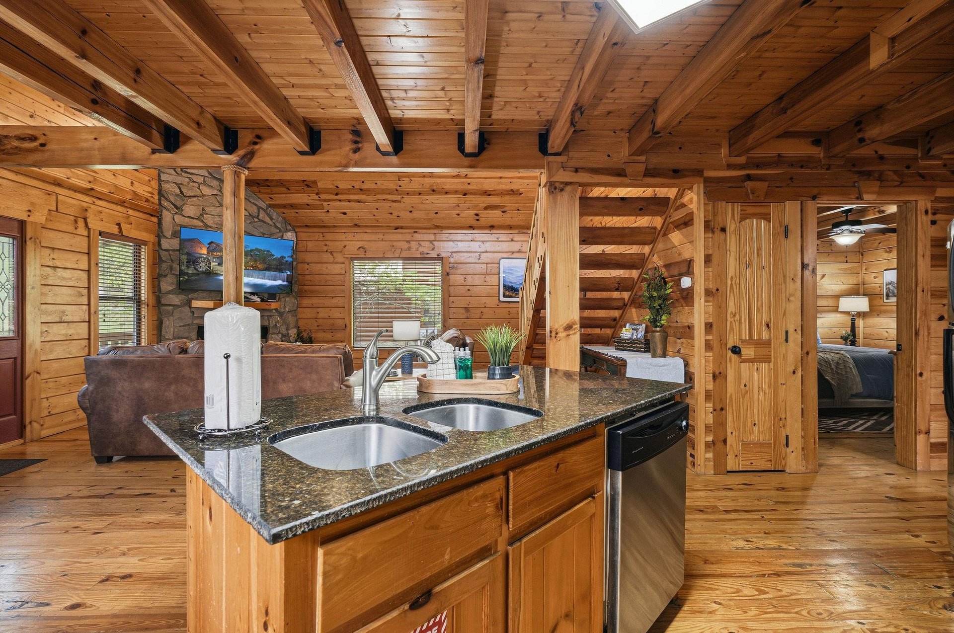 Your rustic kitchen island invites culinary adventures with granite countertops and stainless appliances surrounded by warm wood beams overhead.