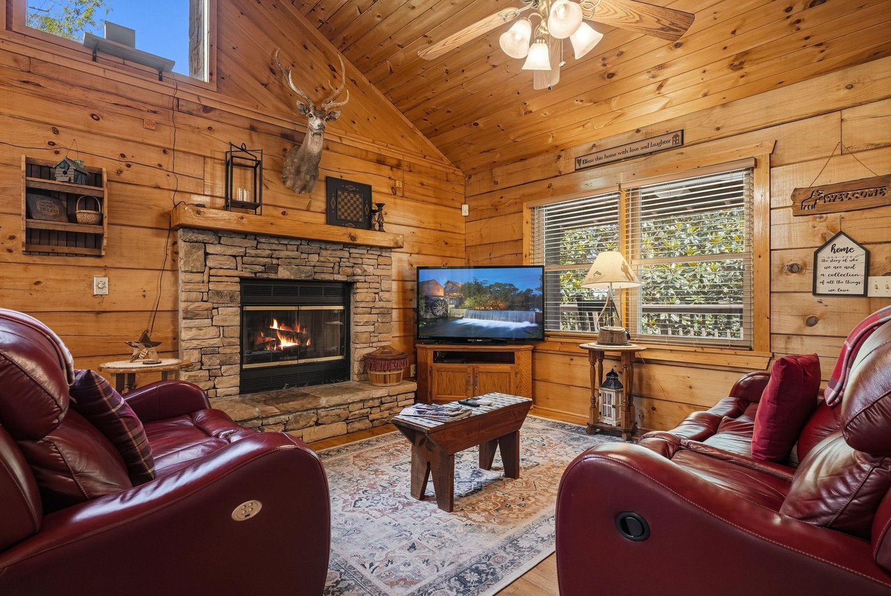 Curl up in plush leather recliners by the crackling stone fireplace, where rustic charm meets total comfort. Your cozy retreat awaits with vaulted wood ceilings and peaceful mountain views.