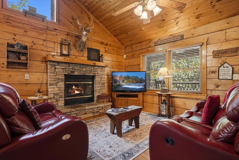 Curl up in plush leather recliners by the crackling stone fireplace, where rustic charm meets total comfort. Your cozy retreat awaits with vaulted wood ceilings and peaceful mountain views.