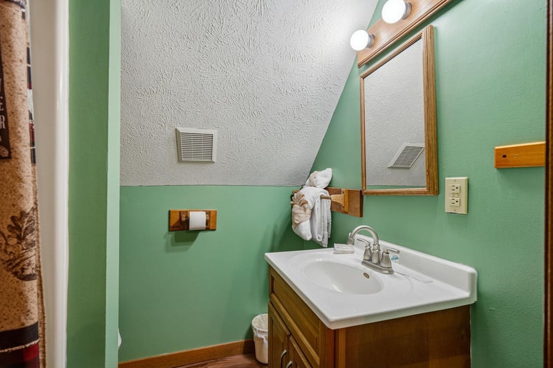 Freshen up in your charming bathroom featuring mint green walls, warm wood vanity, and thoughtful touches like fluffy towels.