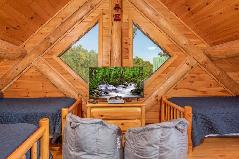 Large windows behind the TV in the bunk room of the game room at Great View Lodge, a 5bedroom cabin rental located in Pigeon Forge