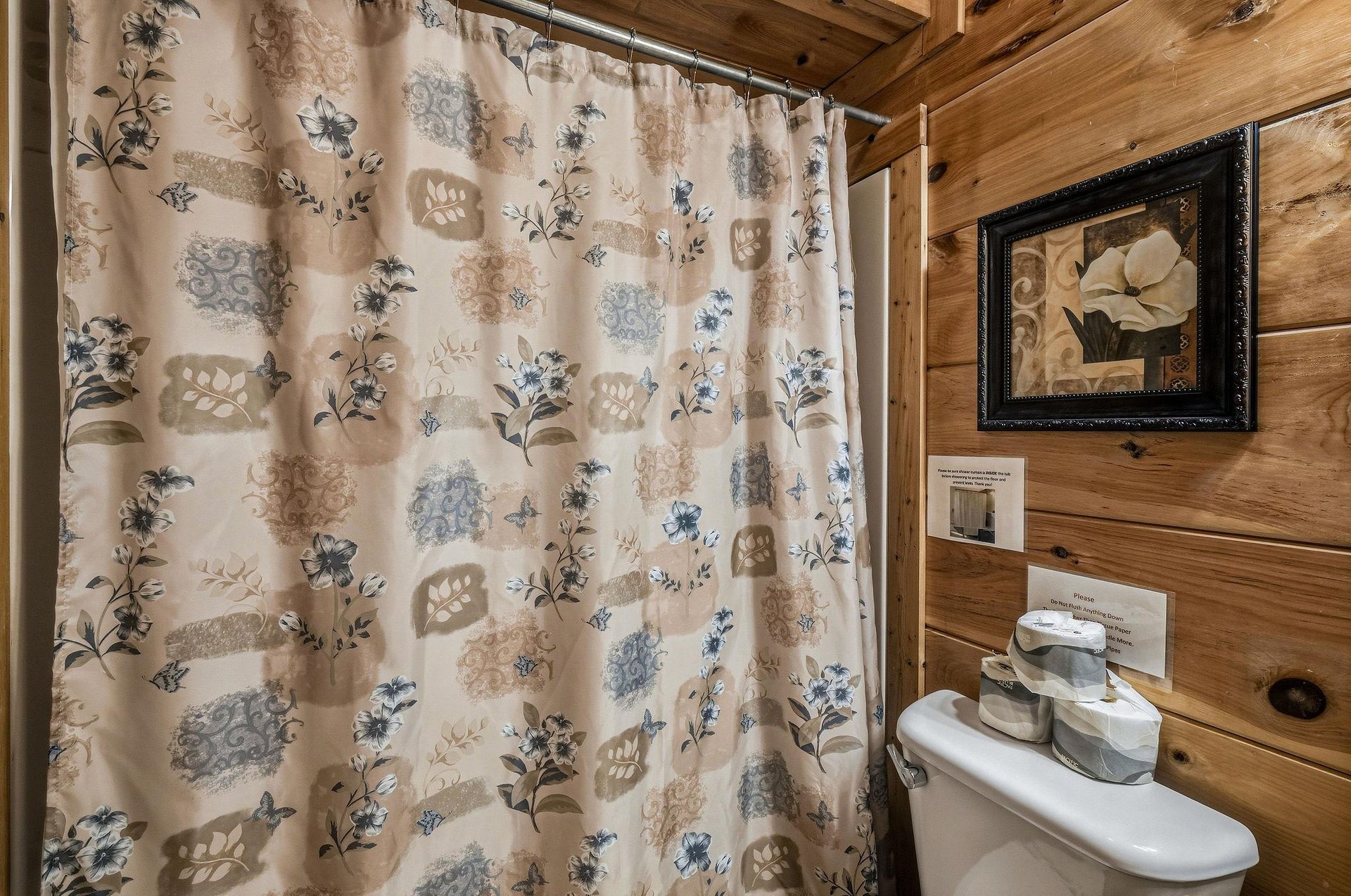 Rustic wood walls create a cozy cabin feel in your private bathroom, complete with charming floral touches and thoughtful amenities.