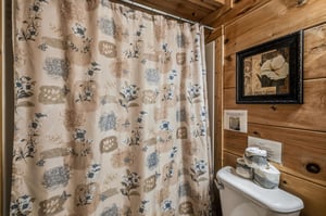 Rustic wood walls create a cozy cabin feel in your private bathroom, complete with charming floral touches and thoughtful amenities.