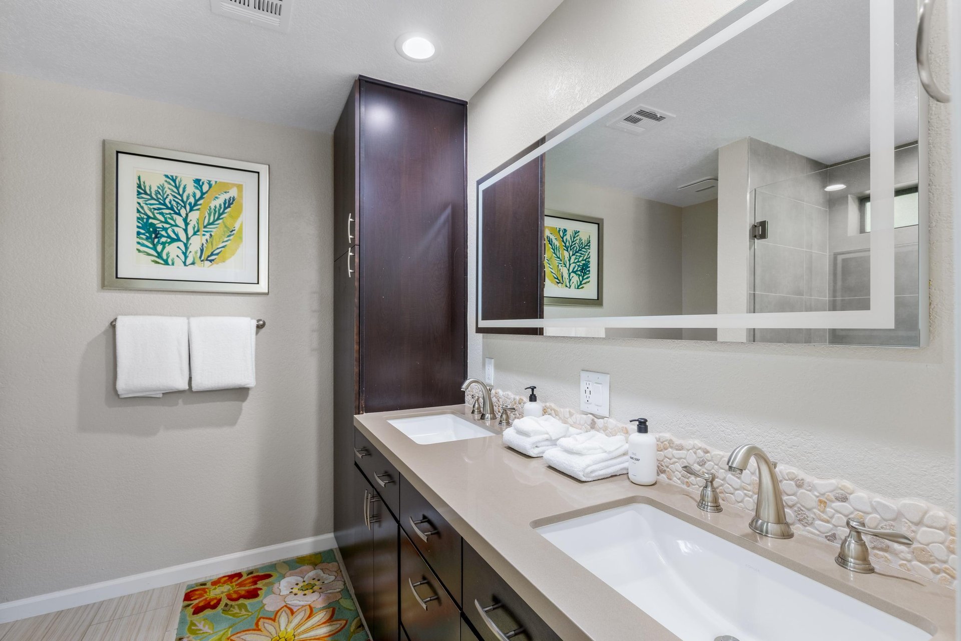 Ensuite primary bathroom with dual vanity sinks and walkin shower.