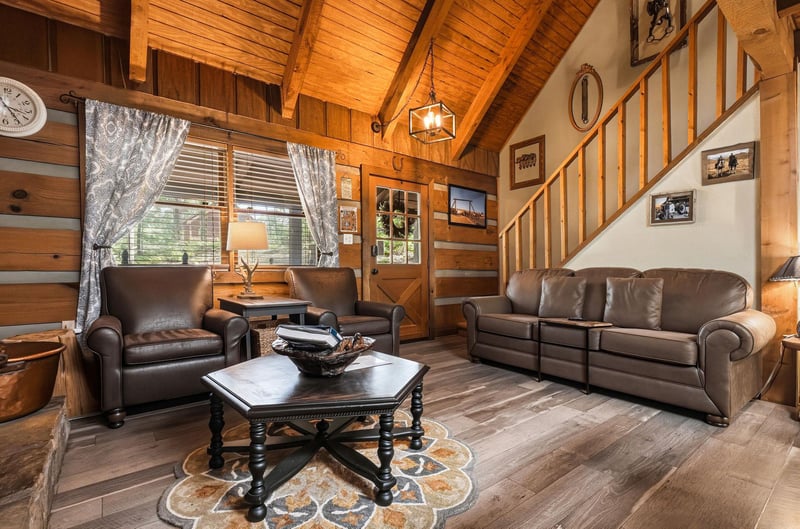Settle into the warmth of this inviting cabin living room, where vaulted wood ceilings and rich leather seating create your perfect mountain retreat.