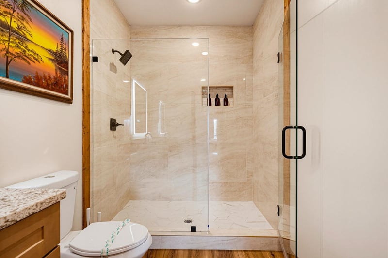 Step into your beautifully appointed bathroom, where a spacious walkin shower with sleek glass doors and warm travertine tile invites you to refresh after a day of exploring.