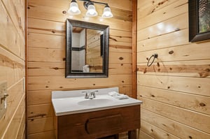 Step into this charming rustic bathroom where warm wood walls create a cozy cabin atmosphere for your mountain getaway.