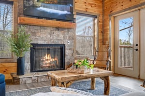 Curl up by your crackling stone fireplace in this cozy living room, where rustic wood beams and warm flames create the perfect retreat.