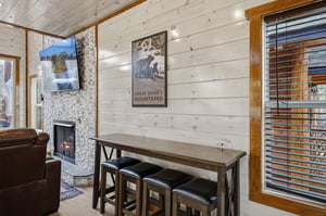 Cozy up by your stone fireplace in this rustic living space, where mountainthemed artwork and warm wood accents create the perfect retreat atmosphere.