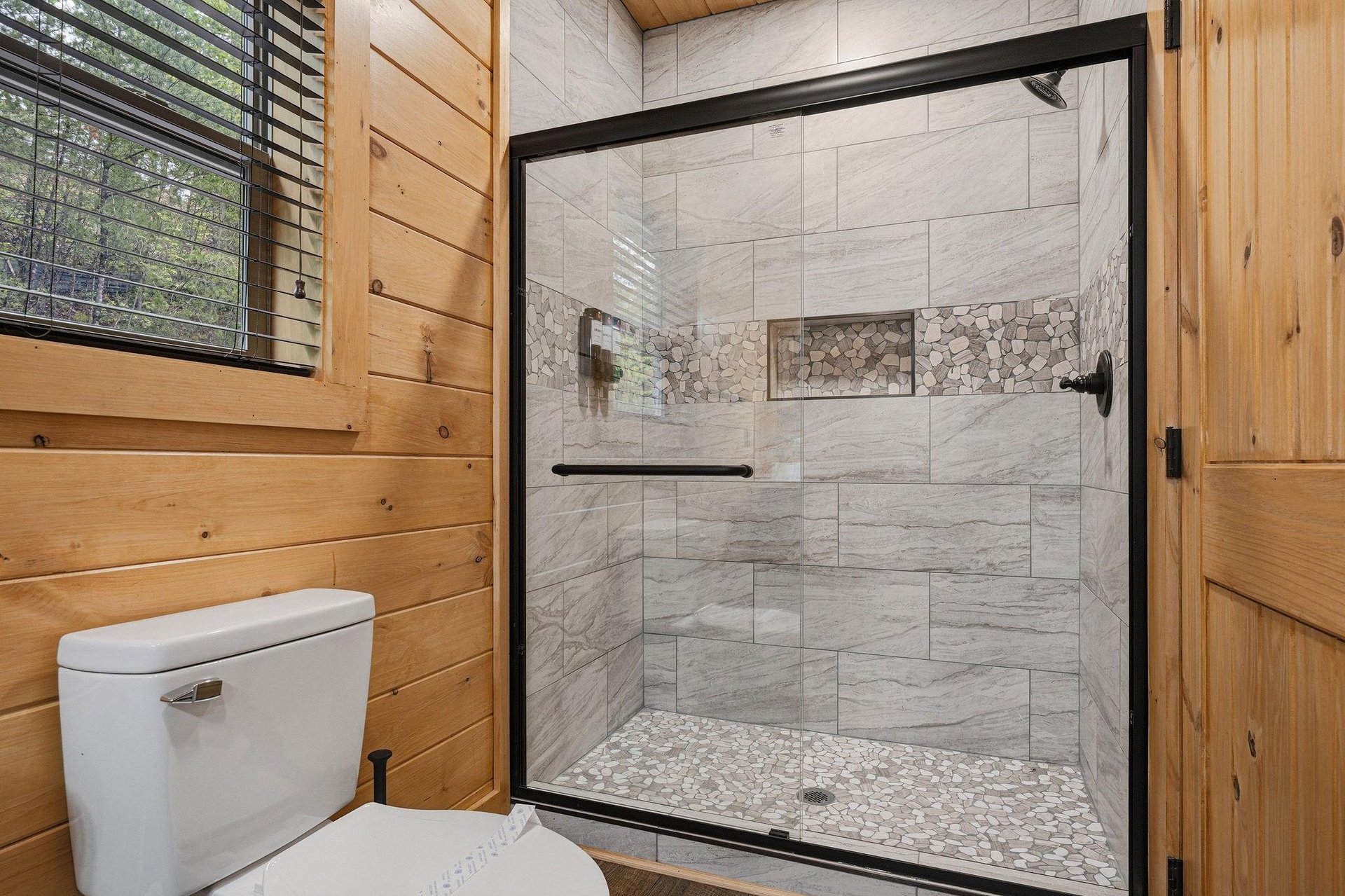 Step into your private spalike retreat with a spacious walkin shower featuring gorgeous stone accents and modern fixtures.