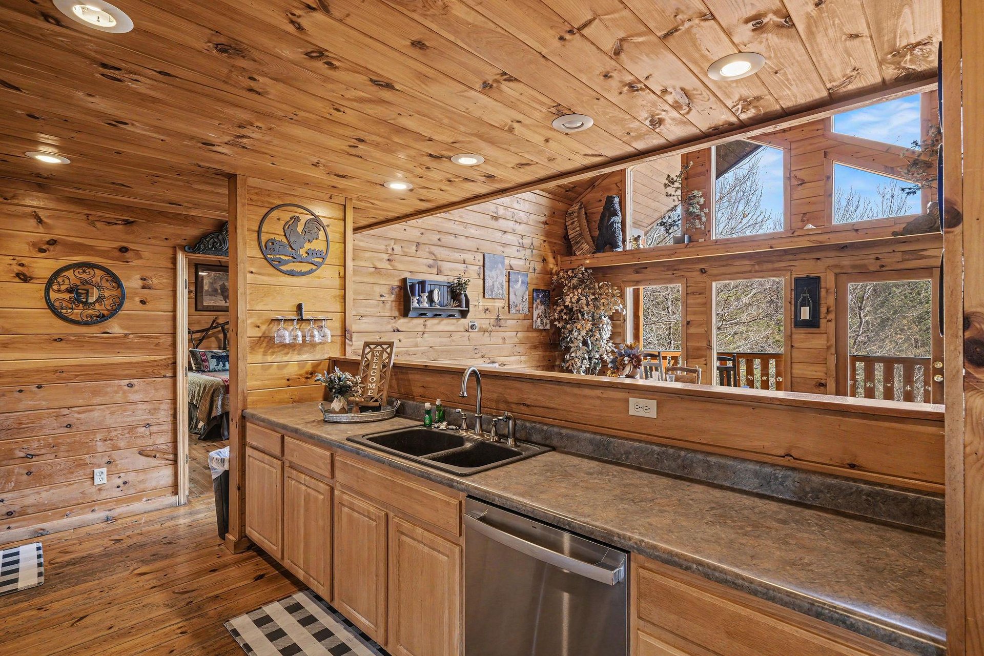 Step into your rustic cabin kitchen where warm wood surrounds you and picture windows frame natures beauty as you cook.