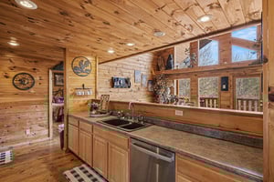 Step into your rustic cabin kitchen where warm wood surrounds you and picture windows frame natures beauty as you cook.