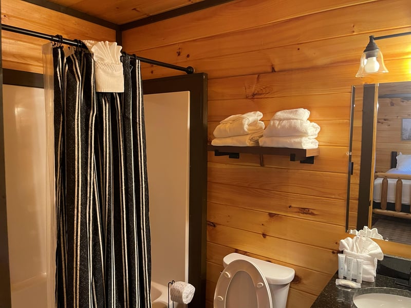Step into a cozy cabinstyle bathroom where rustic wood walls meet modern comfort. Fresh towels await on the shelf, and thoughtful amenities are ready for you.