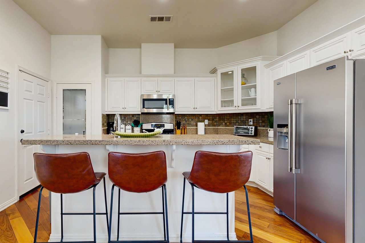 Stainless steel appliances, bar top seating for 3, and granite counters.