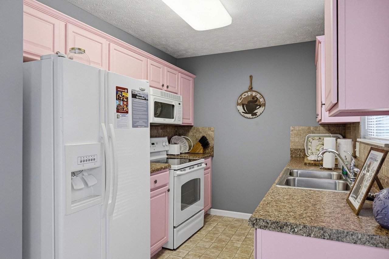Step into your fully equipped kitchen featuring charming pink cabinets, granite countertops, and all the appliances you need for memorable meals.