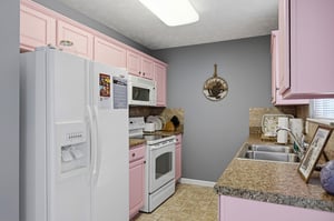 Step into your fully equipped kitchen featuring charming pink cabinets, granite countertops, and all the appliances you need for memorable meals.