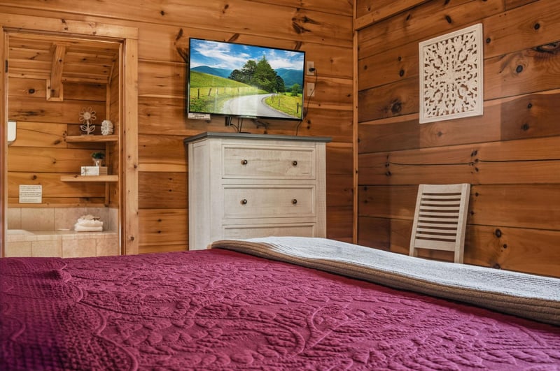 Unwind in this cozy rustic bedroom with warm woodpaneled walls, a plush bed draped in rich burgundy, and charming décor that invites you to relax and recharge.