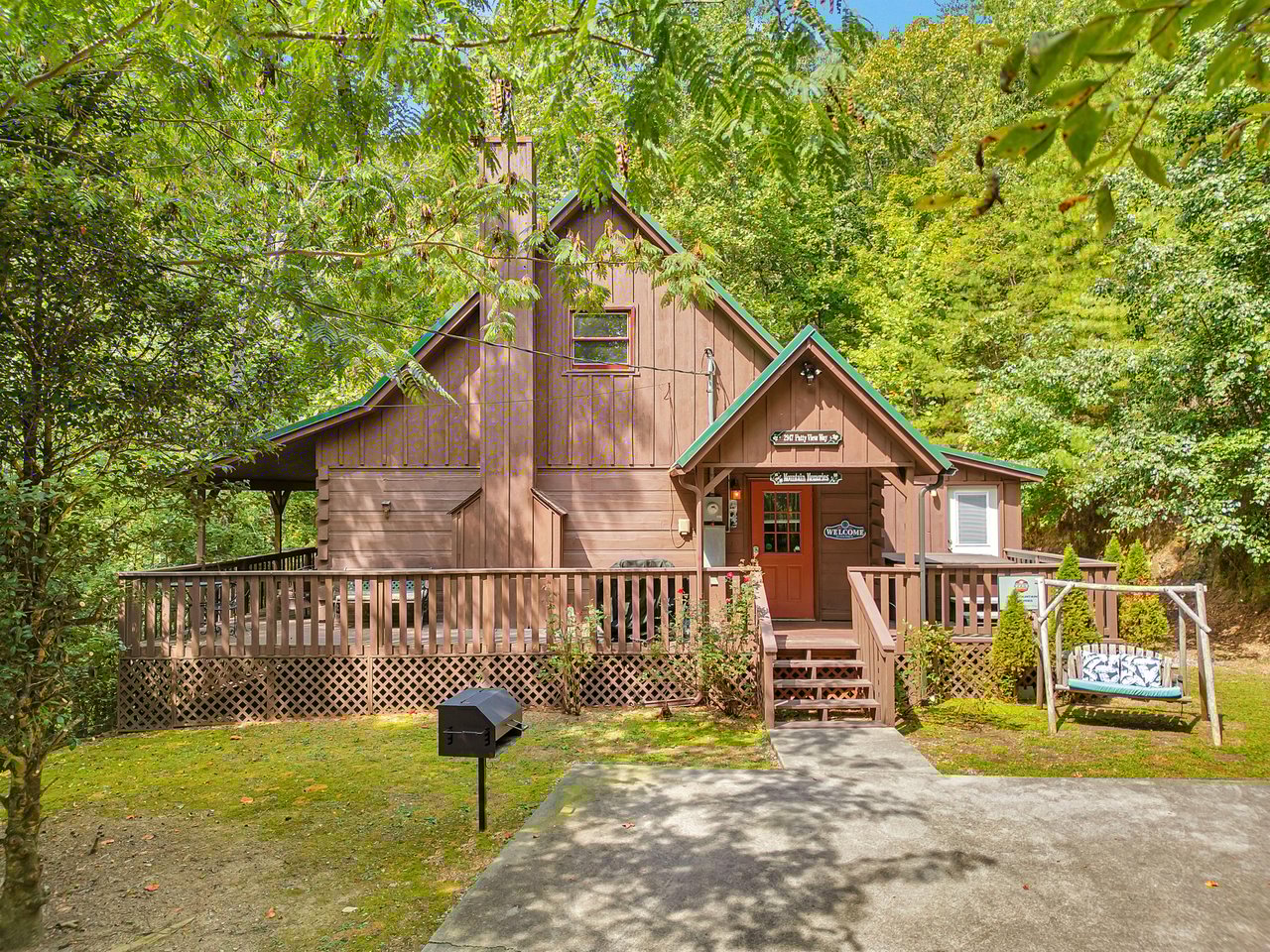 Charming wooden cabin nestled among towering trees, featuring a welcoming wraparound deck and peaceful forest setting for your mountain retreat.