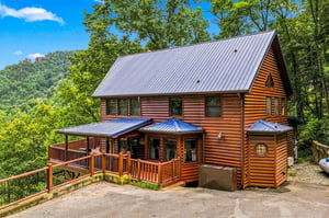 A charming log cabin nestled in the lush mountains, featuring a spacious wraparound deck with scenic views and a distinctive turretstyle room.