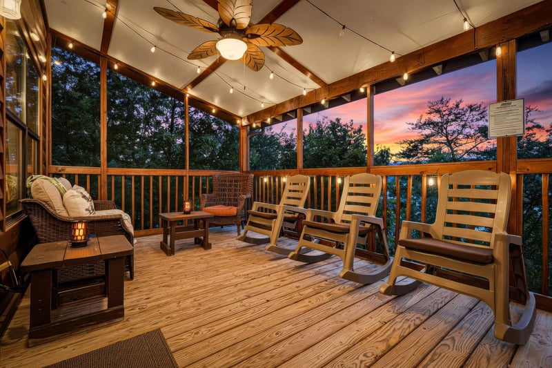 An inviting covered deck awaits, framed by cozy rocking chairs and warm string lighting. As twilight falls, settle in and watch the sky paint itself in brilliant colors beyond the trees.