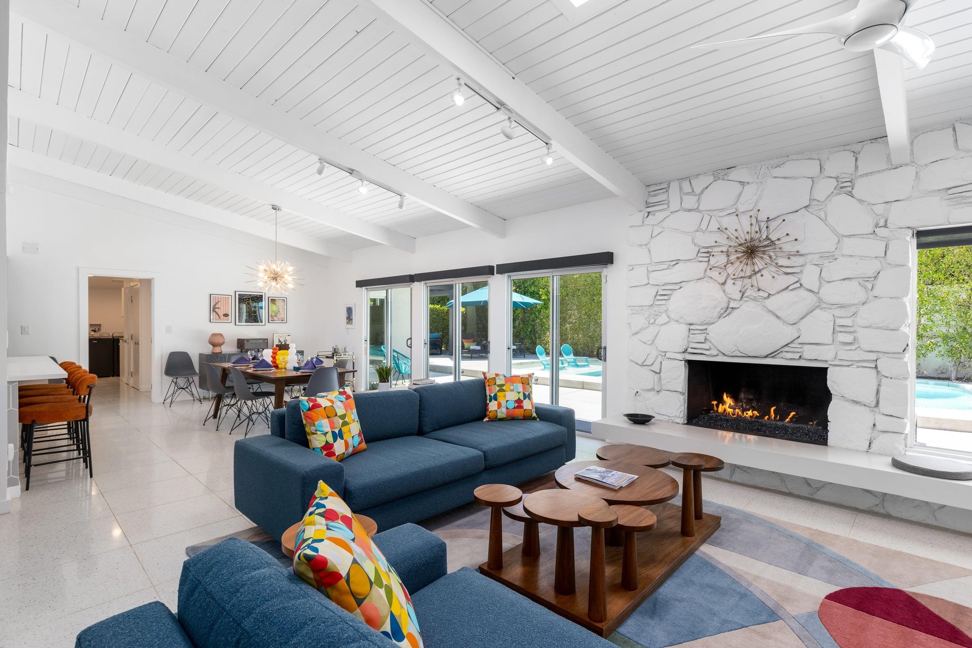 Openliving concept with midcentury modern touches. A fireplace, poolspa views, and flatscreen TV with streaming.