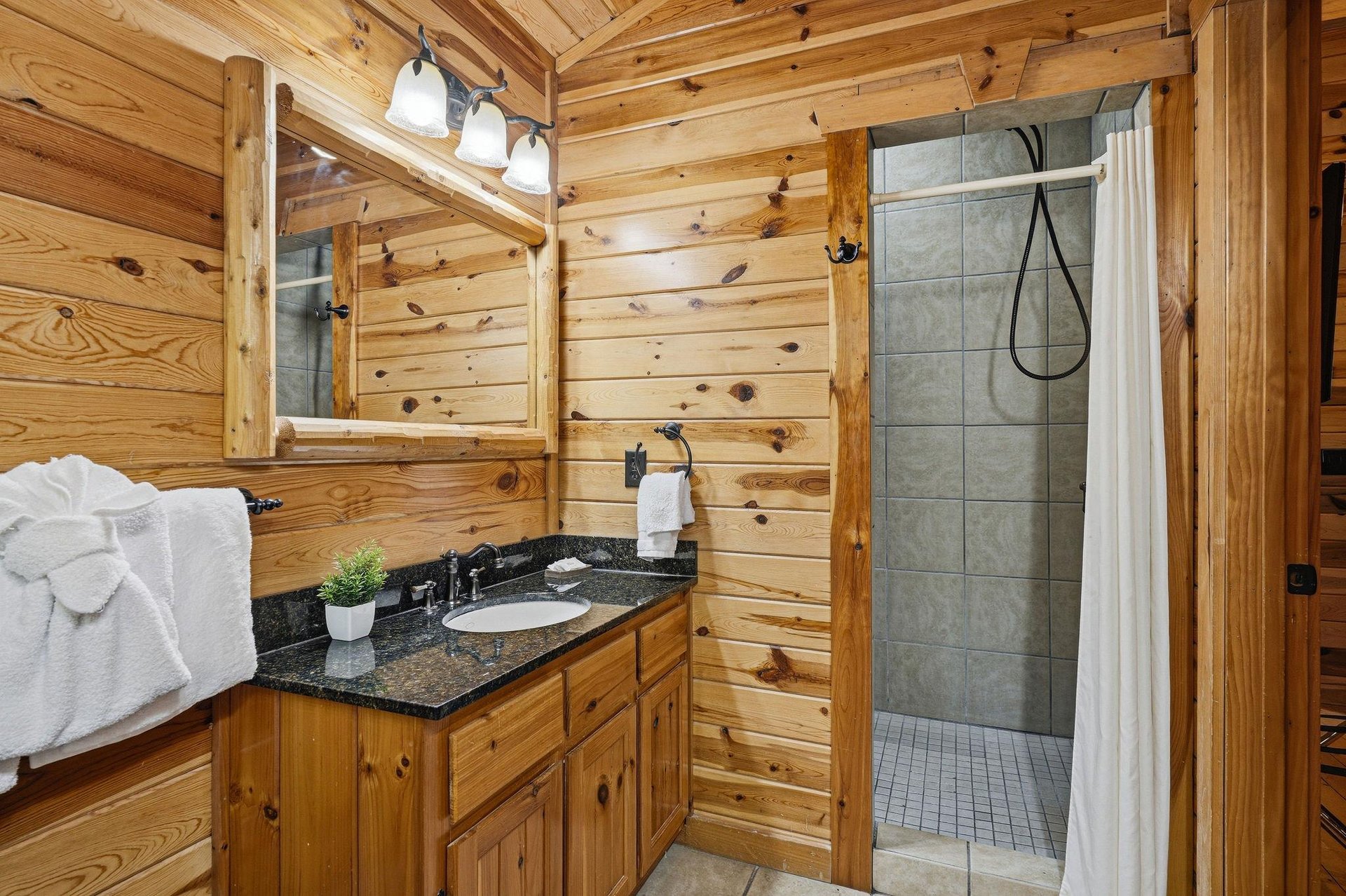 Step into your rustic cabin bathroom with warm wood walls and modern granite vanity for pure relaxation.