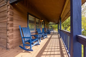 Settle into your favorite blue rocking chair on this welcoming covered porch, where dappled sunlight creates the perfect spot for morning coffee or evening relaxation.