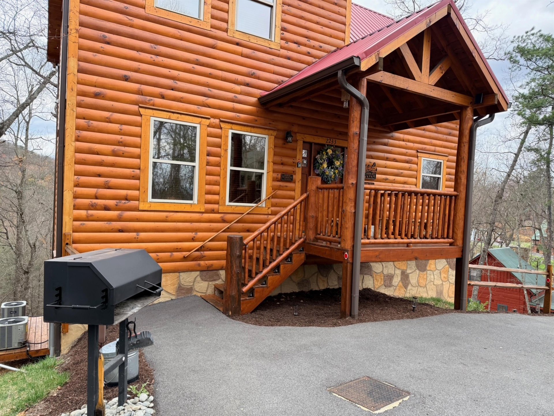 Charming log cabin exterior with covered porch and outdoor grilling station for your mountain getaway.