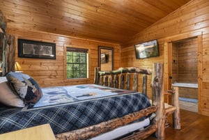Drift off to sleep surrounded by warm wood walls and rustic log furniture in your cozy cabin bedroom.